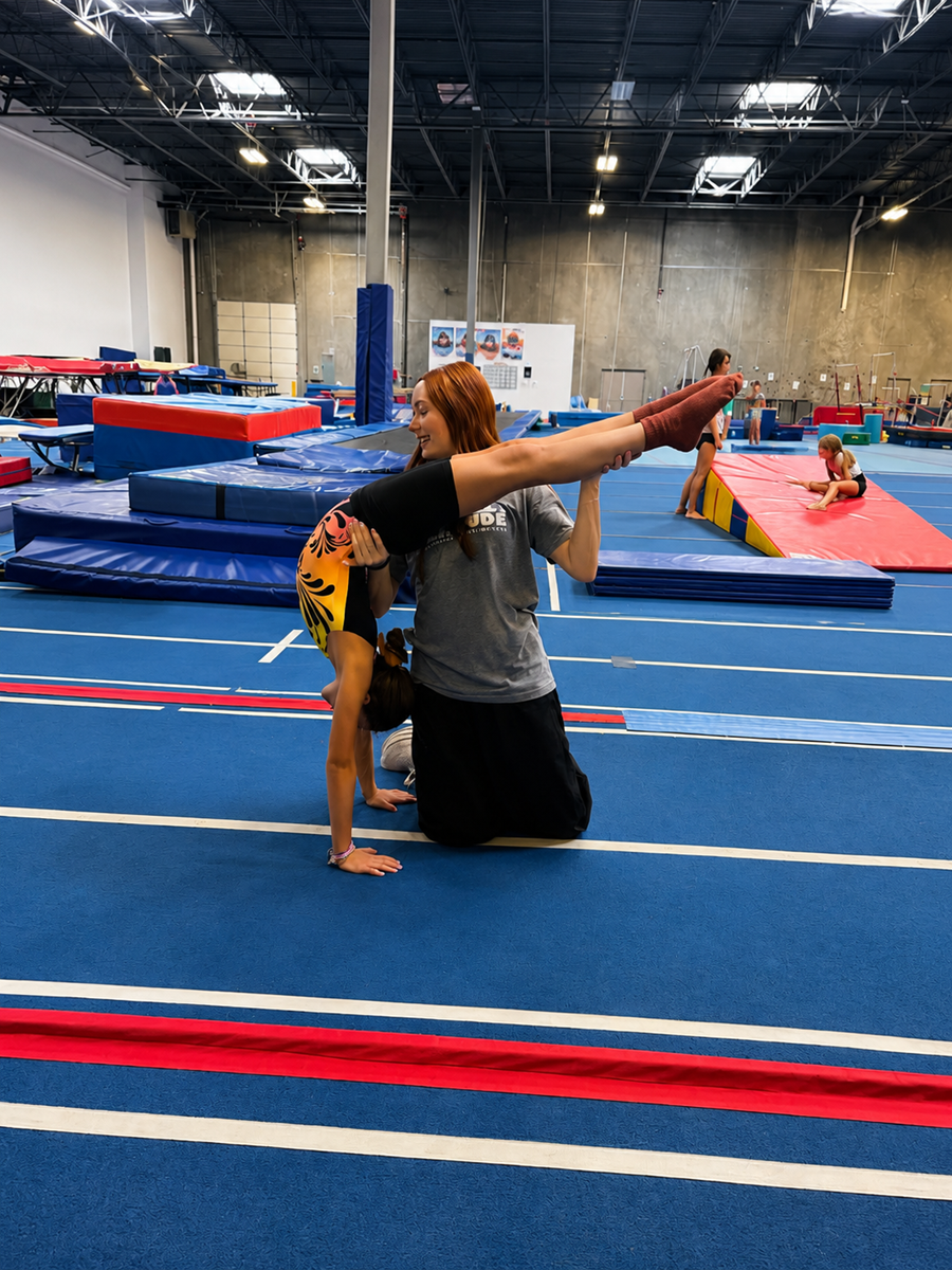 Coach stretching with a young gymnast at High Altitude Tumbling in Provo
