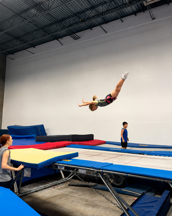 Athlete flipping on the trampoline while a coach spots