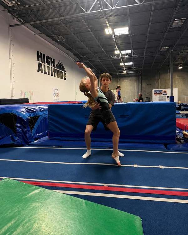Coach spotting a gymnast's floor tumbling pass
