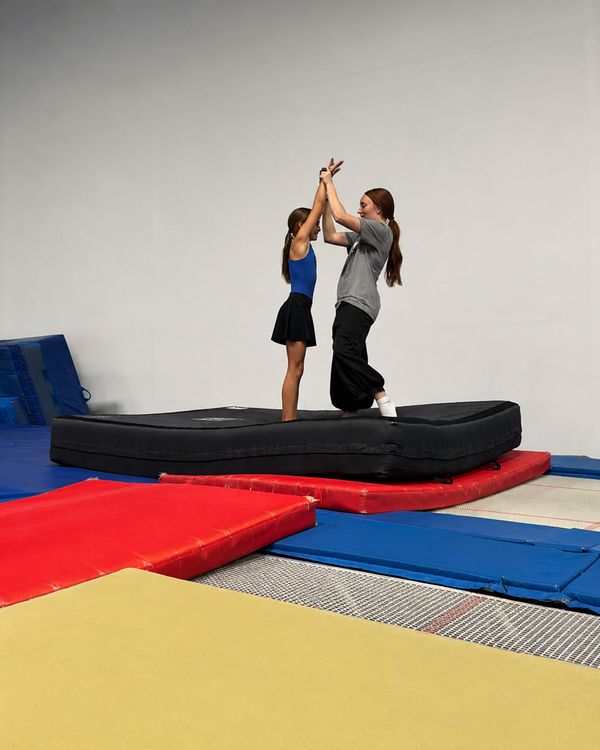Coach high-fiving a young gymnast