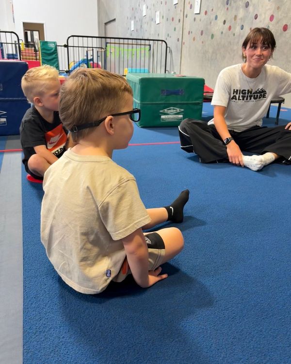 Toddlers sitting in a circle listening to their coach