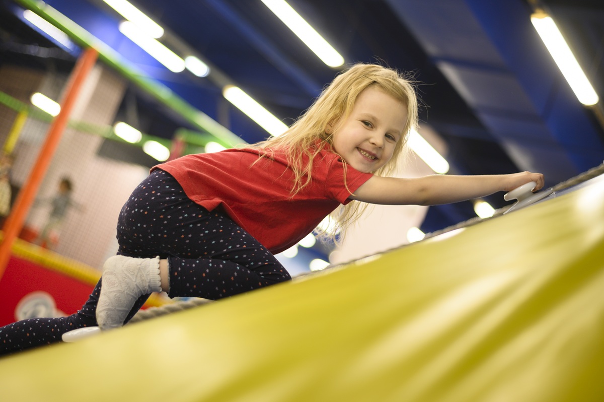 Coach stretching with a young gymnast on colorful mats at High Altitude Tumbling in Provo